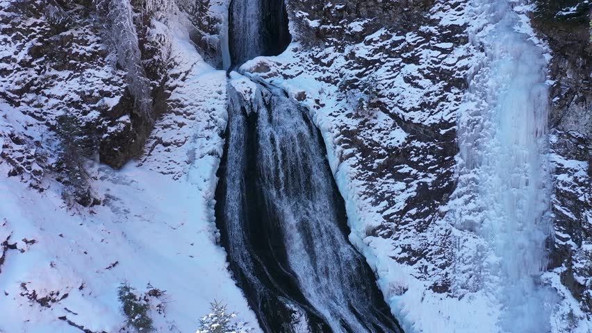 Flying above a frozen waterfall in winter. Rachitele, Romania aerial view by drone