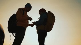 Two hikers check map together while in silhouette against orange sunset beside parked car on roadside nearby showing backpack detail suggesting outdoor travel and adventure for couple planning route - Powered by Shutterstock - Get 15% off with code: PIKWIZARD15
