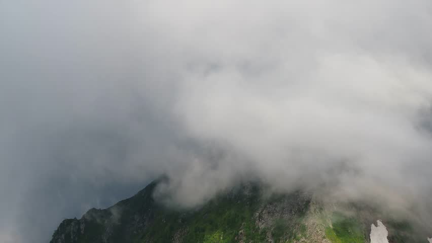 Beautiful mountain landscape. High-mountain massif, clouds over mountain peaks. Mountain slope inside a cloud, nature at a height