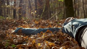 CLOSE UP, LENS FLARE: Playful woman lying in a pile of fallen autumn leaves, making leaf angel. Golden sun shines on the person and through the flying leaves, creating a warm and relaxing atmosphere. - Powered by Shutterstock - Get 15% off with code: PIKWIZARD15