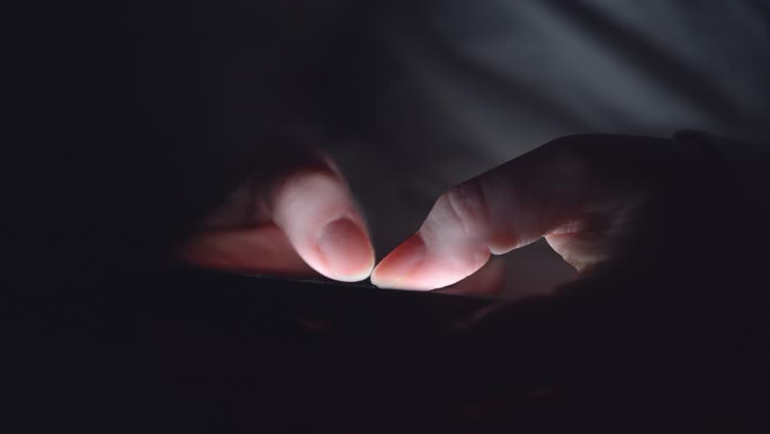 Extreme closeup of woman’s hands using mobile phone in low light, scrolling and searching online late at night. 4K with selective focus.