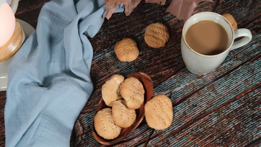 hot drink in blue mug with homemade cookies, dry leaves decoration, fall autumn vibes, rustic cozy seasonal mood