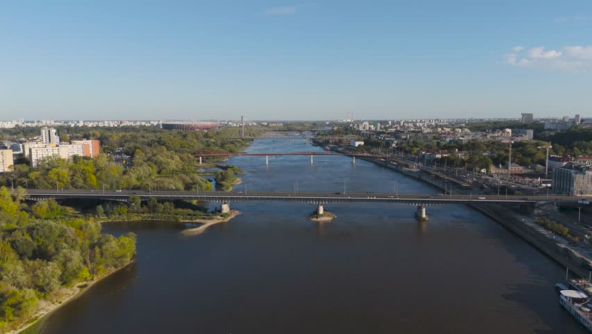 Aerial view of Vistula River reflecting the clear sky, with bridges connecting the banks and cityscape stretching into the horizon, Warsaw, Poland.