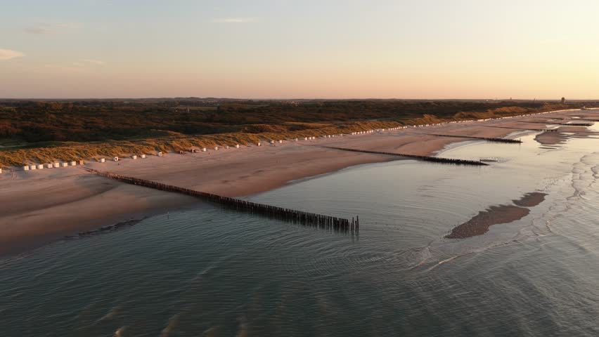 breakwaters at the beach of Zeeland, The Netherlands. Coast line, sunset golden hour.