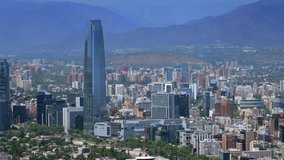 Aerial view of a modern cityscape with a prominent skyscraper, surrounded by diverse buildings and lush greenery, set against a backdrop of distant mountains. - Powered by Shutterstock - Get 15% off with code: PIKWIZARD15