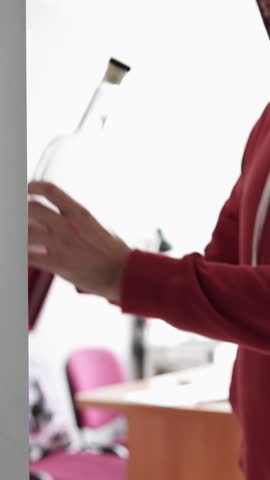 Man opens fridge and grabs alcohol bottle in quiet kitchen.