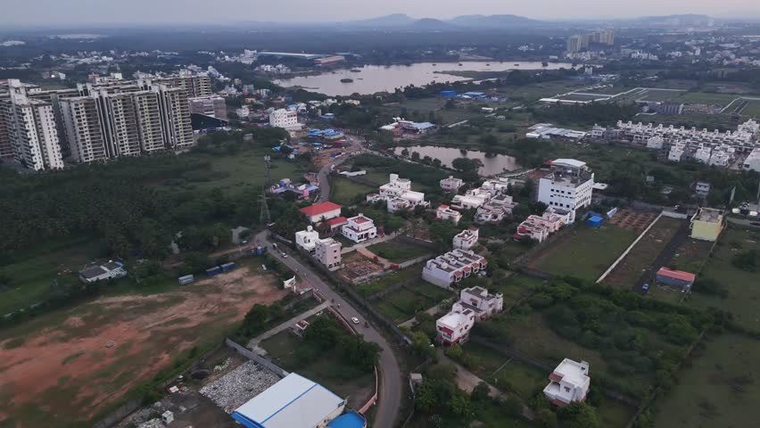Wide-angle footage of urban expansion at dusk. The clip shows a large, placid lake framed by new residential and commercial buildings, highlighting the balance between nature and rapid city growth.