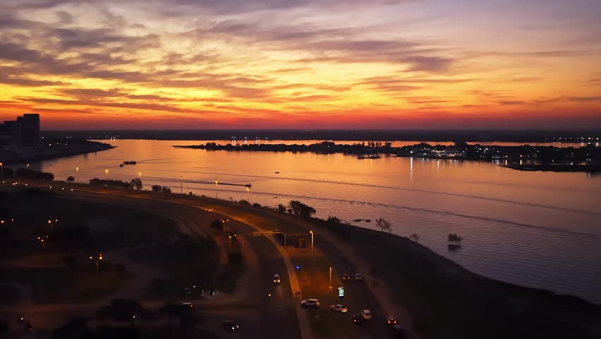 Dramatic sunset over Costanera Avenue and Paraguay River with boats and city skyline in Asunción, Paraguay