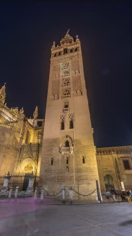 La Giralda and Seville Cathedral timelapse hyperlapse at night, glowing with golden lights. The historic bell tower, gothic details and illuminated streets create magical atmosphere in Seville, Spain