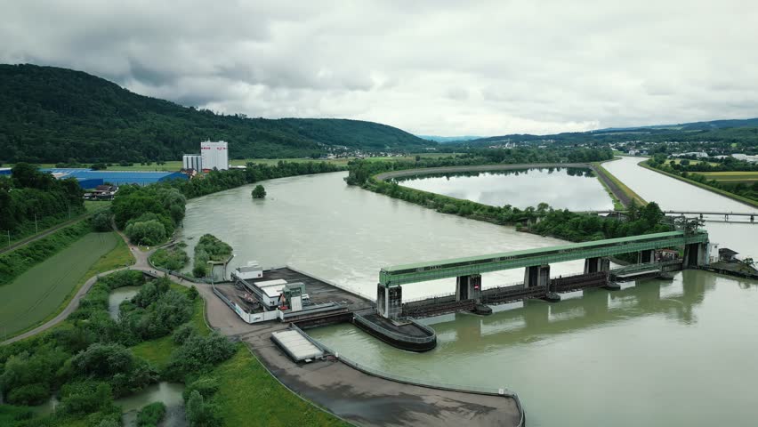 Huge hydroelectric dam with cascading water stream and full-flow relief gates and big water reservoir in South Germany, aerial view