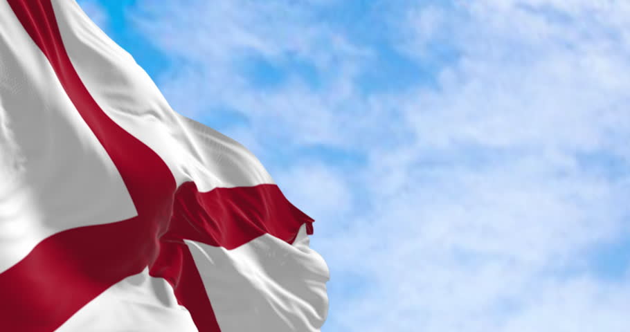 Close-up of Alabama state flag waving on a sunny day. The flag of Alabama features a red cross on a white field. Seamless 3d render animation. Slow motion loop. Selective focus