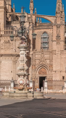 Seville Cathedral entrance and Fuente Farola fountain on Plaza de Virgen de los Reyes city square timelapse. Walking place in downtown with historic architecture. Seville, Andalusia, Spain.