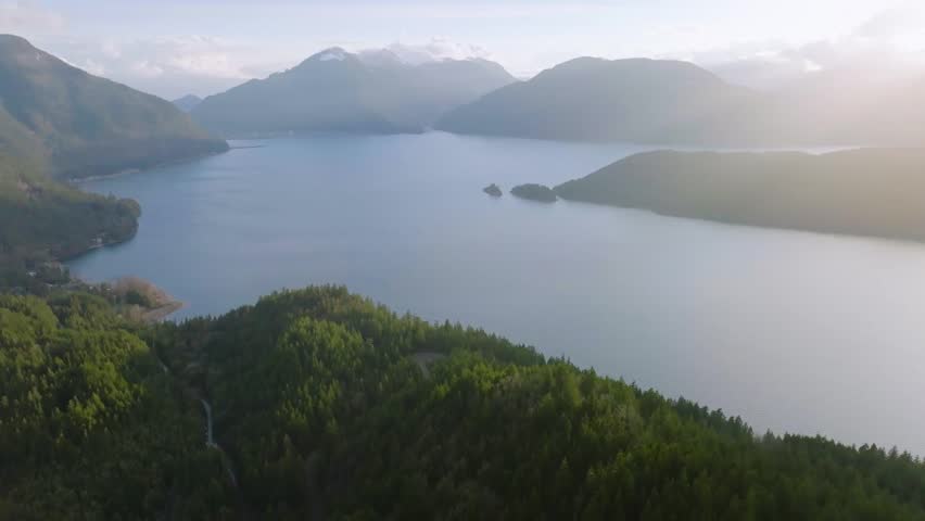 Aerial view of Harrison Lake and surrounding forest with a majestic mountain landscape in the background, capturing pristine nature and serenity.