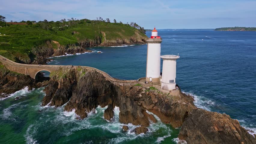 Petit Minou Lighthouse on rocky islet, stone causeway, sea with waves, Plouzané, Brittany, France. Aerial drone lateral view