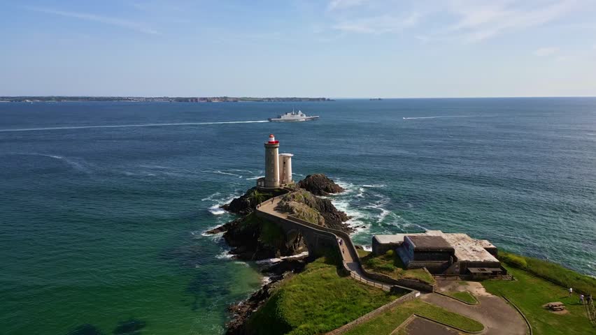 Petit Minou Lighthouse with warship in background, France. Aerial forward, Plouzané, Brittany, France