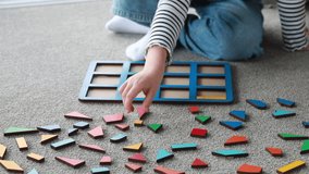 The child arranges colorful geometric shapes in a frame. Children's educational wooden puzzle game - Powered by Shutterstock - Get 15% off with code: PIKWIZARD15