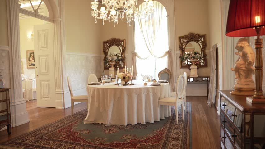 round dining table with white linens, candles, and floral centerpiece in a refined classic room