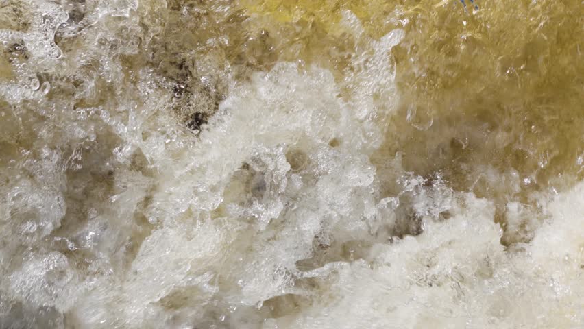 Close-up of the wildly splashing colored tannic water of a waterfall.