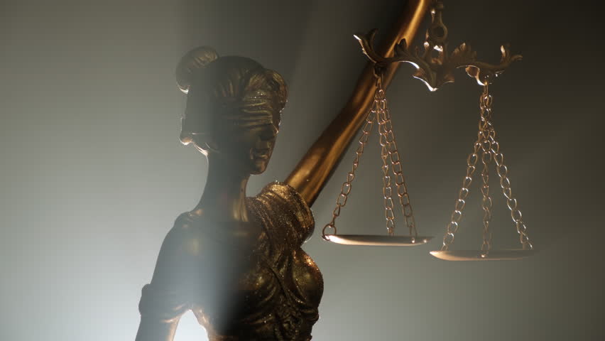 Golden statue of goddess themis with scales of justice of backlight on gray dark background