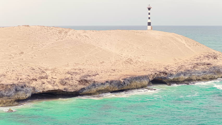 Aerial view of Varandinha shore,beach is divided by rocks that outline its contour creating a wonderful landscape,in the end of the rocks there a lighthouse close-up,Boa Vista,Cape Verde.