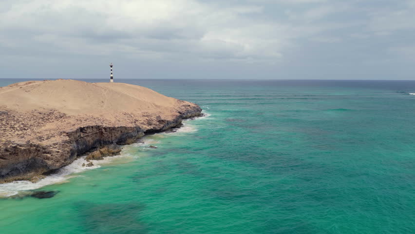Nice Aerial shot of Varandinha shore,beach is divided by rocks that outline its contour creating a wonderful landscape,in the end of the rocks there a lighthouse,Boa Vista,Cape Verde.