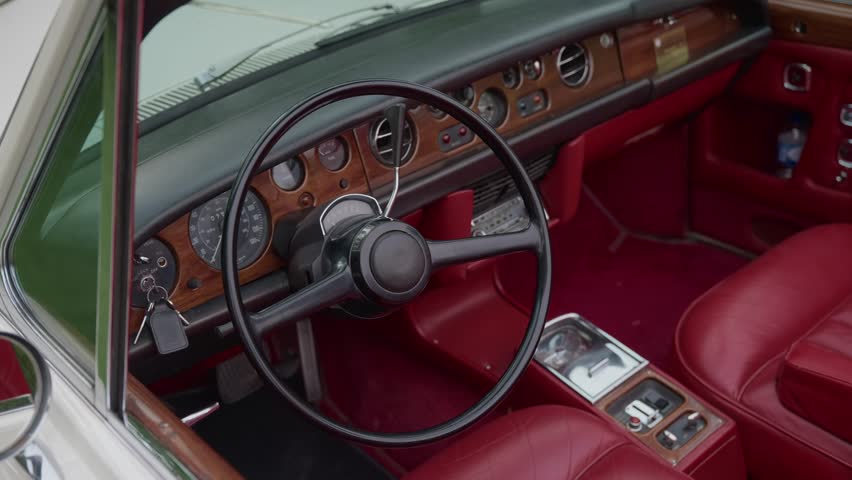 interior of a vintage classic car featuring red leather seats steering wheel and wooden dashboard details