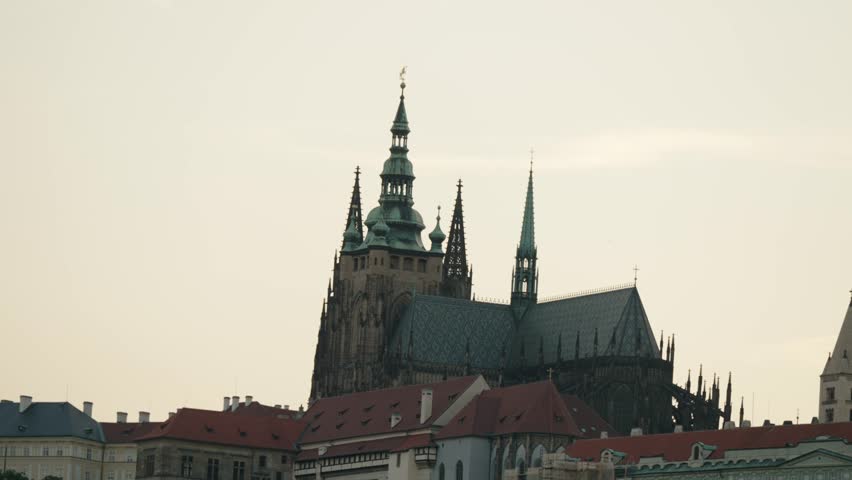 St. Vitus Cathedral with gothic spires rising over historic rooftops in Prague, Czech Republic, during dusk light