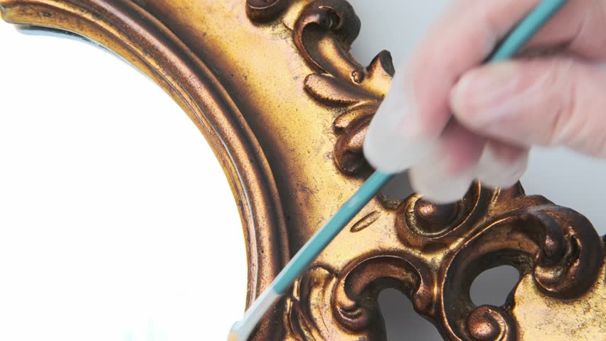 Antique artwork detail, restorer working with brush, gold frame cleaning, closeup historical artifact before sale, art object ready for expert evaluation and auction