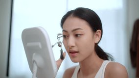 Asian young woman using eyelash curler before applying mascara, smiling in mirror during morning beauty routine. Natural makeup look for long curled eyelashes.
 - Powered by Shutterstock - Get 15% off with code: PIKWIZARD15