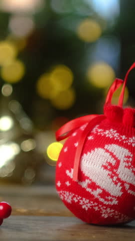 Christmas vertical video. Knitted Red Christmas decoration ball, festive bokeh lights on background. Cozy xmas home decor.