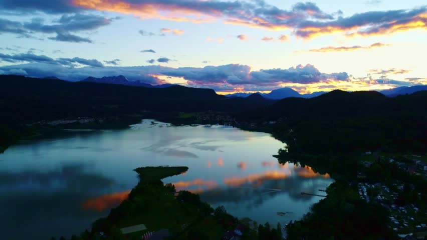 Austria lake, sunset with reflections of colorful clouds over mountain horizont