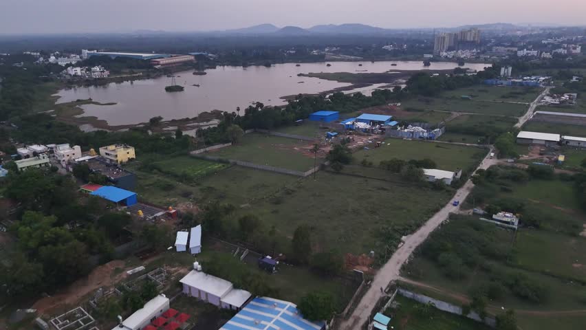 Aerial view of Mambakkam lake located in Chennai near Vandalur. Wide-angle footage of urban expansion at morning. The clip shows a large, placid lake framed by new residential and commercial buildings