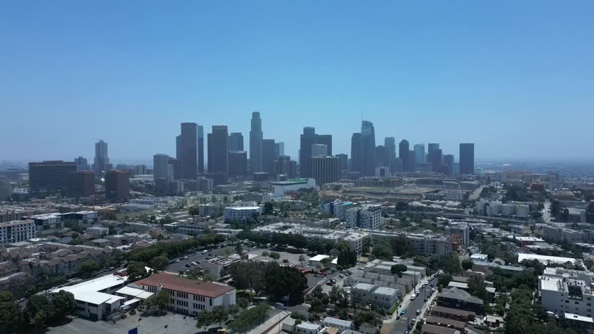 Aerial drone shot flying over Los Angeles houses revealing the city skyline in 4K 60FPS. Calm, cinematic view of urban life and architecture.