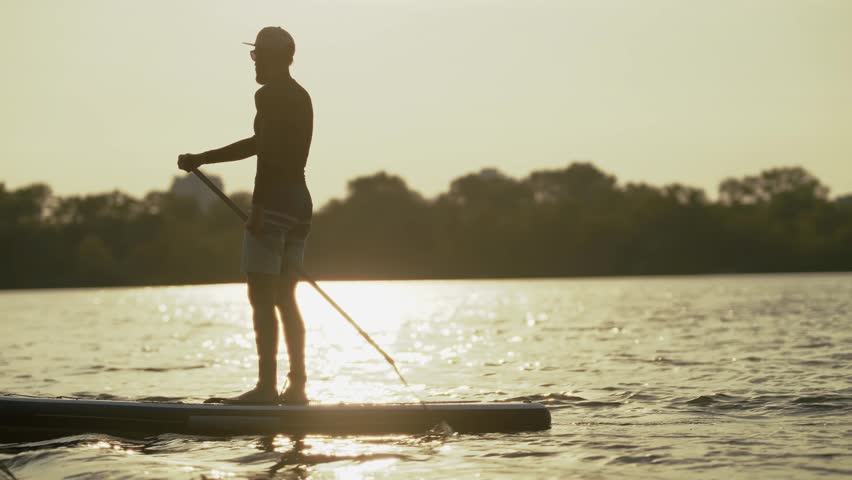 SUP Stand Up Paddleboard. Outdoor Summer Recreation. Paddling On  Calm River. Enjoying The Sunset On Water. Healthy Lifestyle And Sport. Paddleboarding Hobby. Peaceful Evening SUP Paddling  Exercise