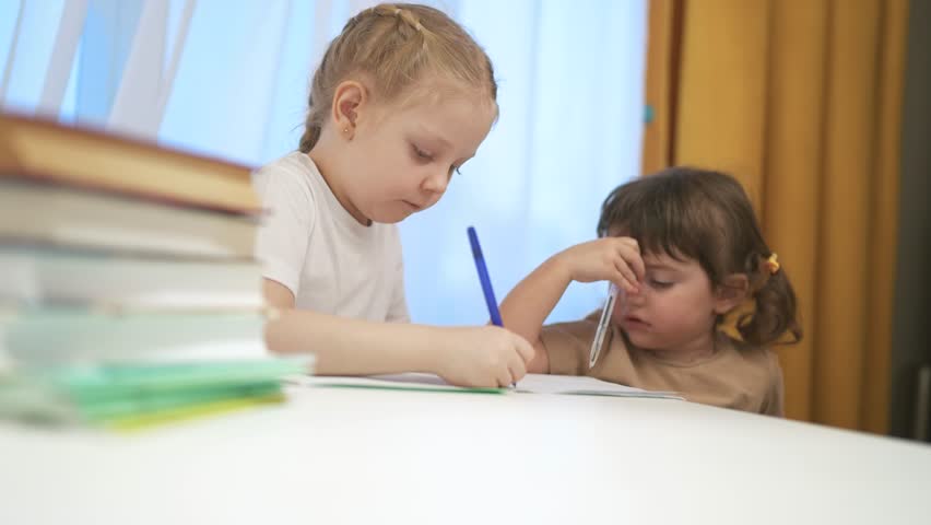 Two children sitting at table with laptop. Group of children are doing remote lessons on lifestyle laptop. Young girl is using a laptop to learn about distance education. A pair of kids are at a.