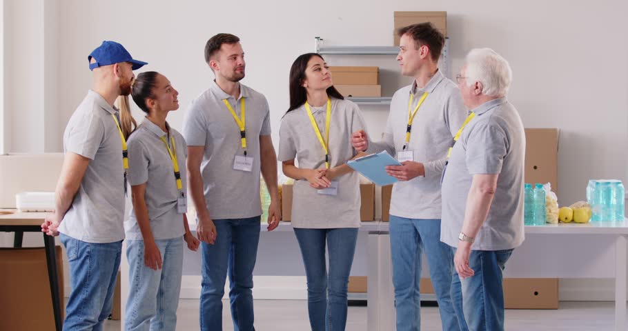 Group of happy smiling volunteers working together in charitable foundation and giving high five each other finishing job. Volunteering, donation and humanitarian aid concept. 4k video.