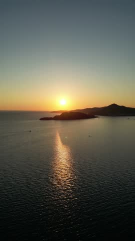 Aerial drone video of sunset over the Budva coastline in Montenegro. Golden reflections on the sea with mountains and islands in the distance. Perfect for travel, tourism, and motivational projects.