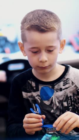 A small inventor creates robots, machines from different parts of the designer. the boy of 10 years, plays in the designer from cubes, plates, circuits, wires.
