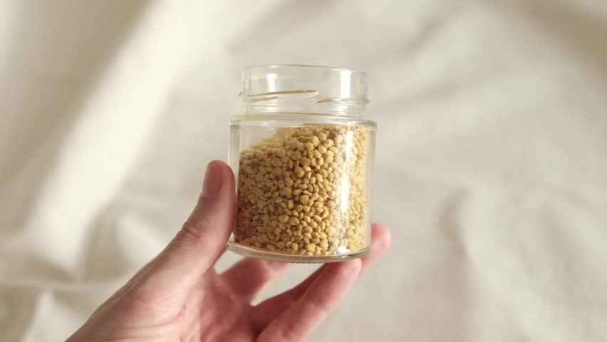Bee pollen granules in a jar. Rotating a small jar containing bee pollen in granules. Natural super food packed with minerals and vitamins. Boost immune system with natural healthcare product.