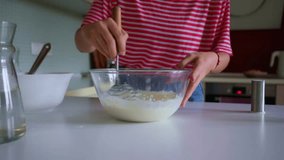 Close-up of a person in a red striped shirt whisking batter in a glass bowl on a kitchen counter, preparing homemade food. - Powered by Shutterstock - Get 15% off with code: PIKWIZARD15