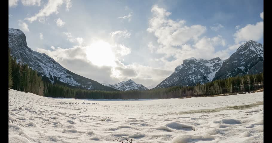 Mountain and cloudy sky at a emerald blue lake landscape. Windy day at the lake blow tress and water making strong currents. Environment when seasons change in North American territory.