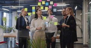 Motivated team happy planning discussing creative startup ideas on sticky papers, employees looking at stickers, successful result, modern workers brainstorming behind modern glass office wall - Powered by Shutterstock - Get 15% off with code: PIKWIZARD15