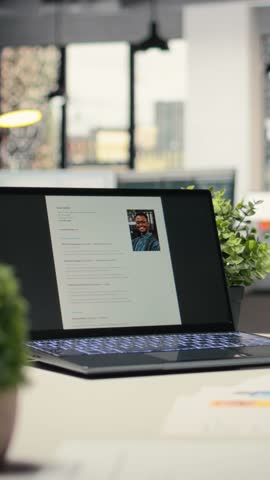 Vertical Video Modern desk with laptop in empty office shows applicant CV before hiring interview, office used for the recruitment process and reviewing qualifications or work experience to align with