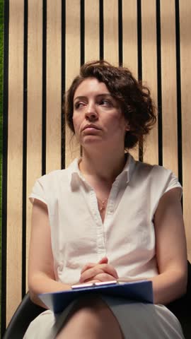 Vertical Video Scared impatient woman applicant getting extremely nervous and agitated while she waits in the queue outside HR office. Person sitting in line under pressure, deals with anxiety. Camera