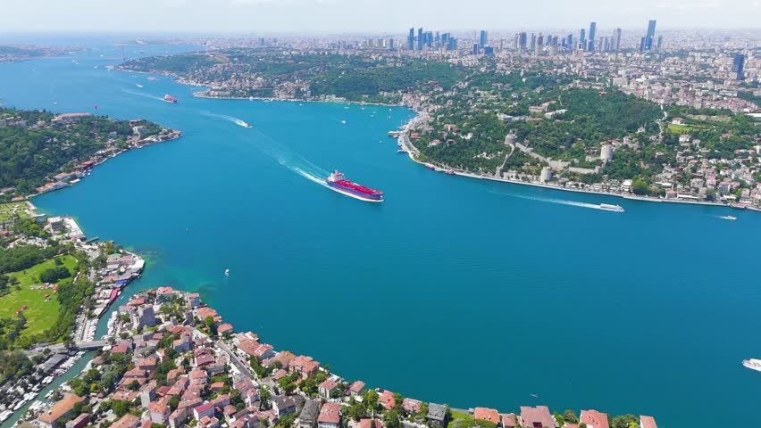 Istanbul, Turkey. Red and blue cargo ship approaches the Fatih Sultan Mehmet Bridge. The Bosphorus Strait between Europe and Asia. Sunny day, Aerial View