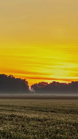 Sunset With Vibrant Orange Sky Over A Peaceful Rural Landscape - Vertical Shot, Timelapse