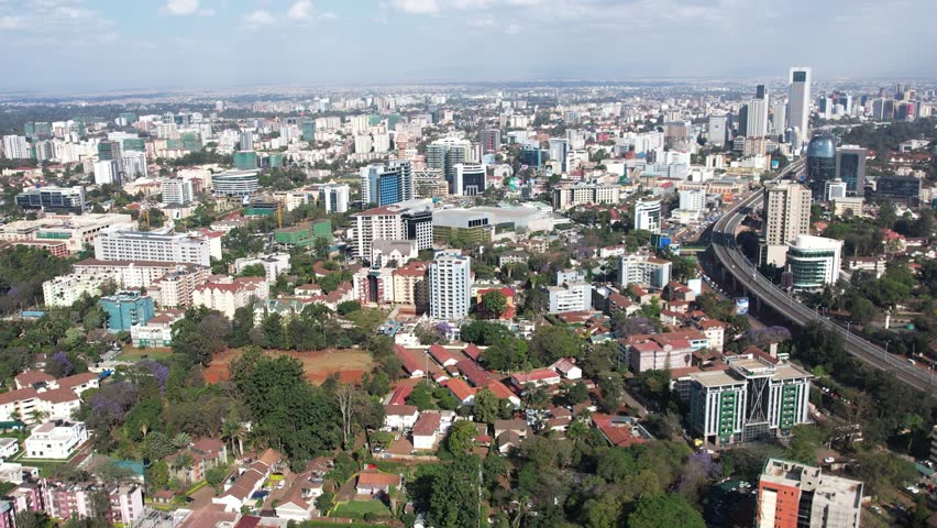 A beautiful aerial drone footage of the city of Nairobi, Kenya, showcasing the bustling urban office spaces, modern residential areas, the Nairobi Expressway, and Waiyaki Way. Captured during the day.