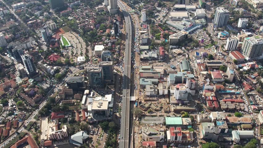 A beautiful aerial drone footage of the city of Nairobi, Kenya, showcasing the bustling urban office spaces, modern residential areas, the Nairobi Expressway, and Waiyaki Way. Captured during the day.