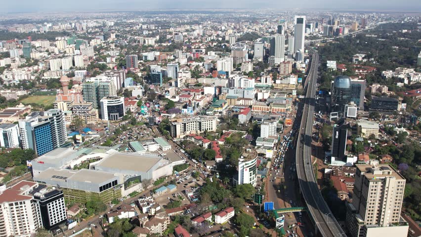 A beautiful aerial drone footage of the city of Nairobi, Kenya, showcasing the bustling urban office spaces, modern residential areas, the Nairobi Expressway, and Waiyaki Way. Captured during the day.