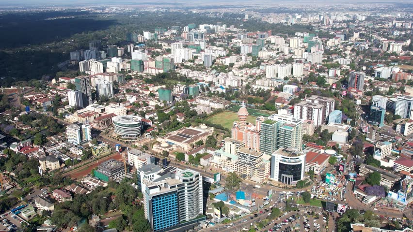 A beautiful aerial drone footage of the city of Nairobi, Kenya, showcasing the bustling urban office spaces, modern residential areas, the Nairobi Expressway, and Waiyaki Way. Captured during the day.